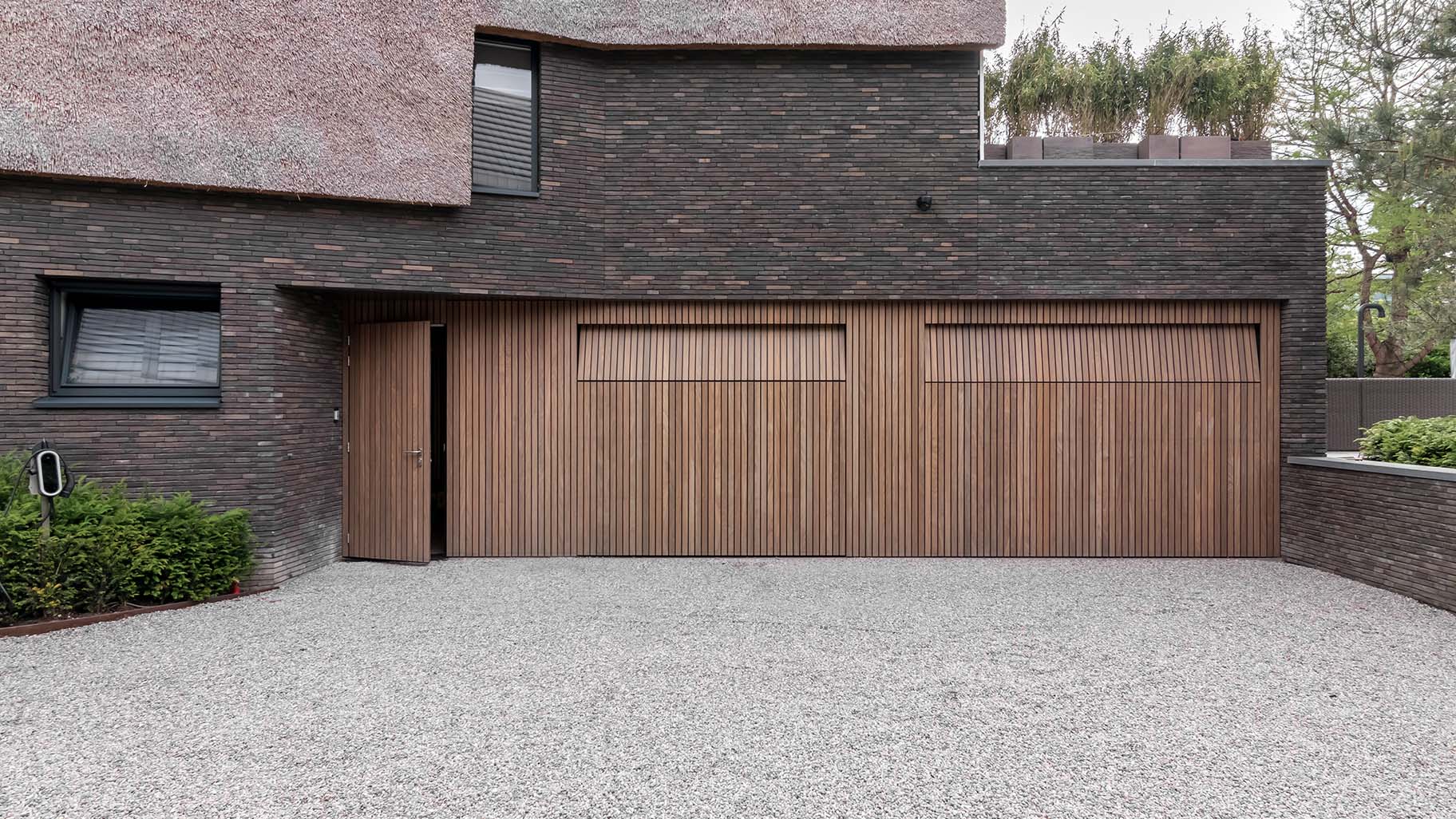 Afrormosia houten garagedeuren en loopdeur gelijk met de gevel