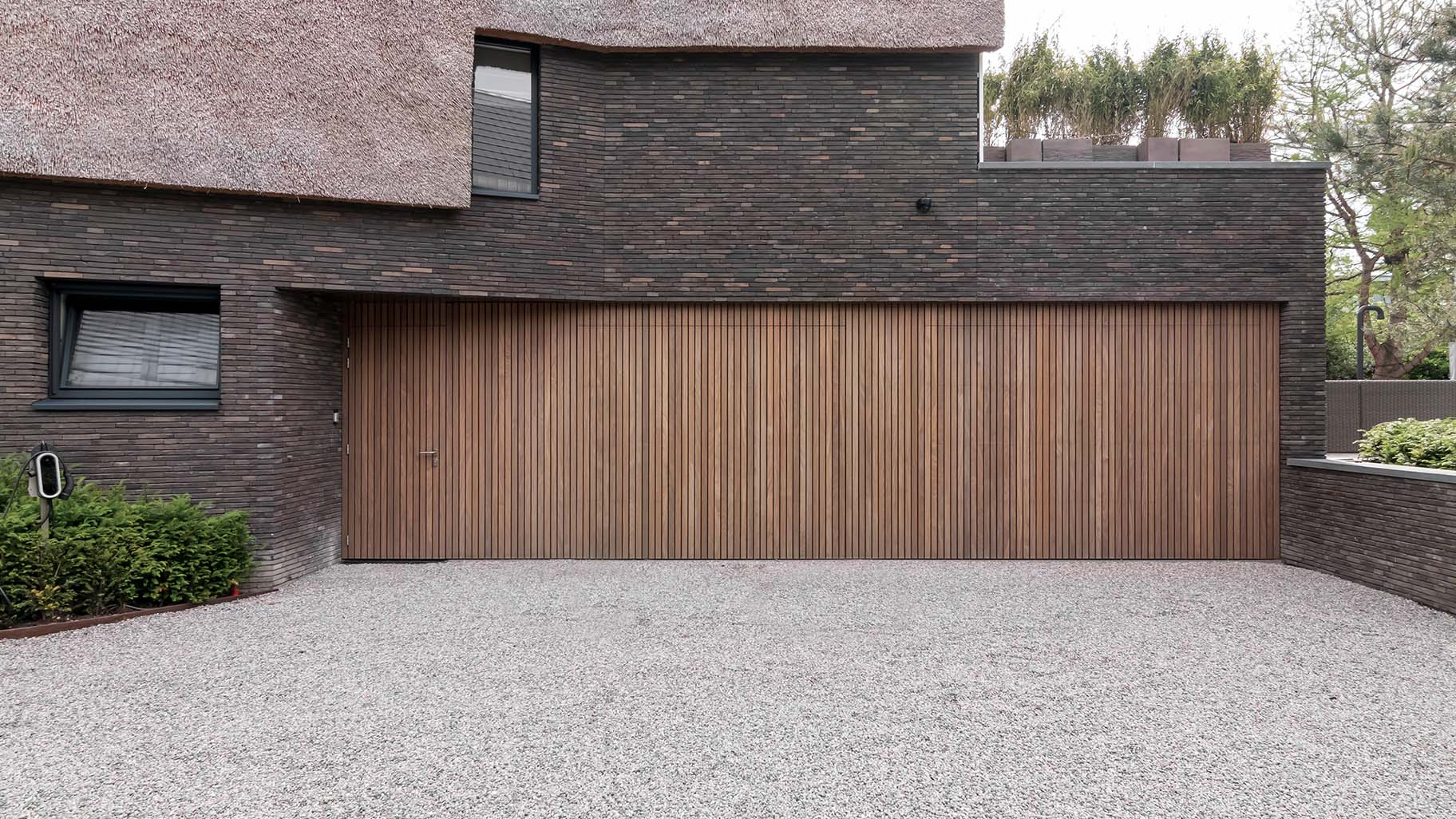 Moderne woning met twee garagedeuren en een loopdeur van Afrormosia hout