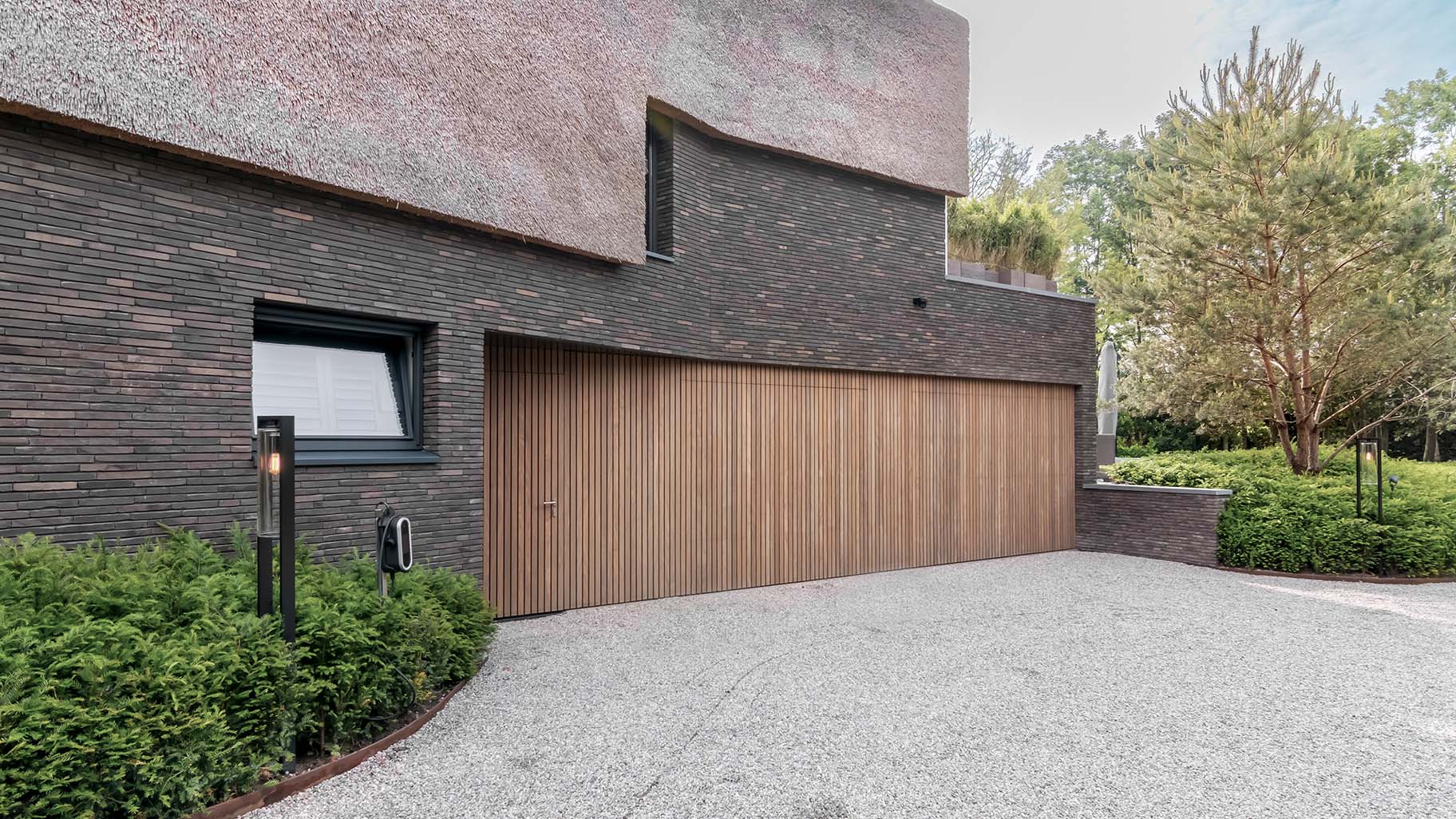 Afrormosia houten garagedeuren en loopdeur gelijk met de gevel