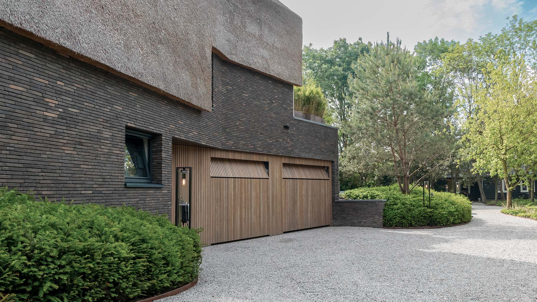 Afrormosia houten garagedeuren en loopdeur gelijk met de gevel