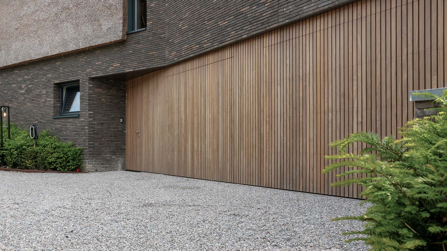 Afrormosia houten garagedeuren en loopdeur gelijk met de gevel