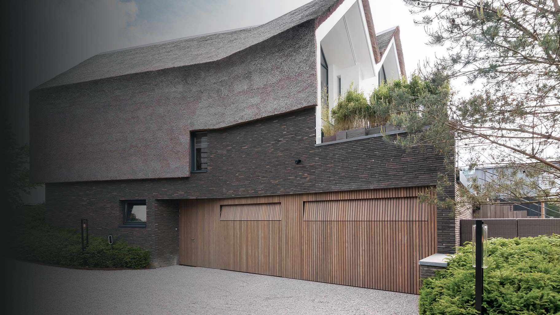 Moderne woning met twee garagedeuren en een loopdeur van Afrormosia hout