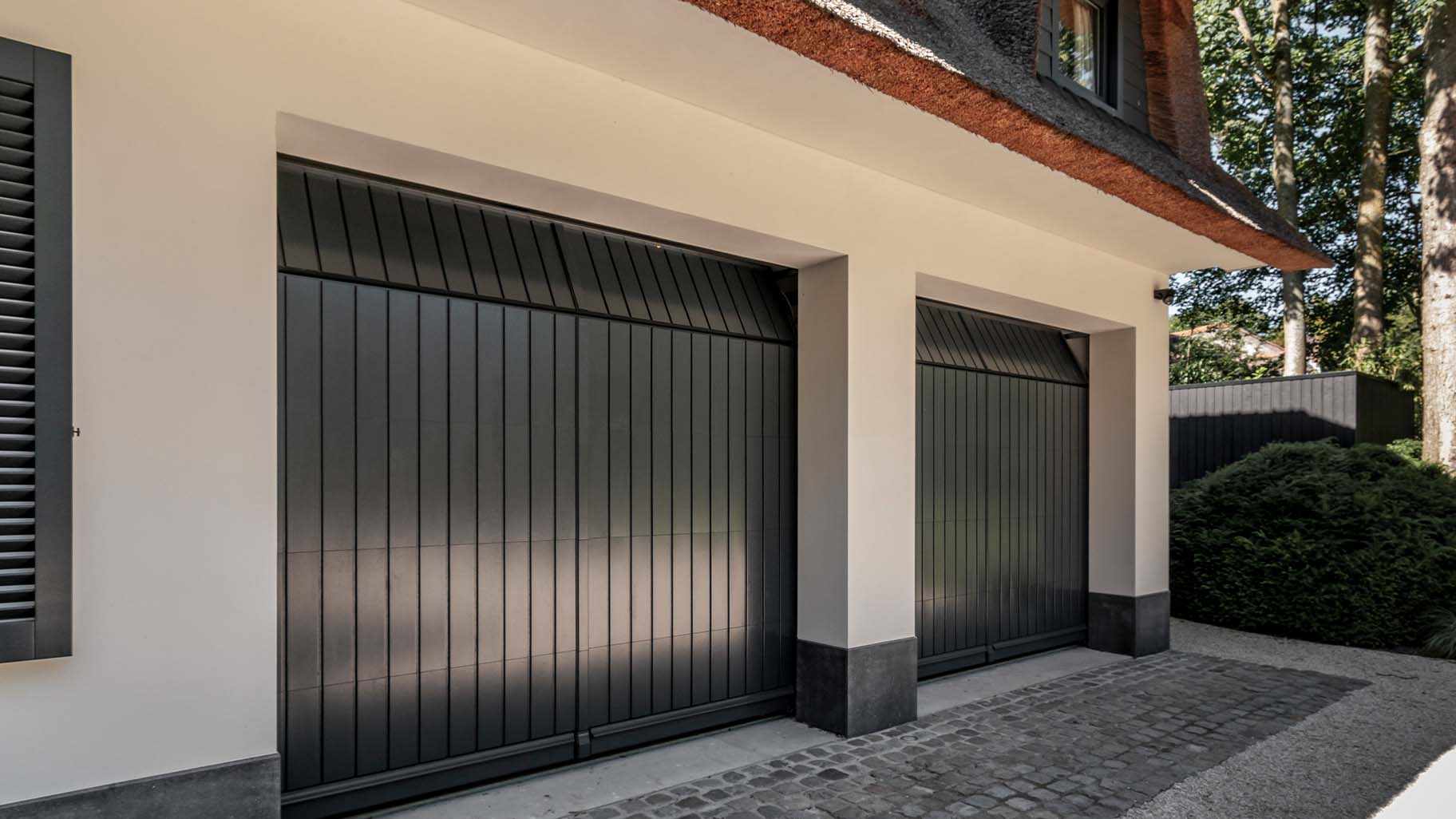 Twee op maat gemaakte houten sectionaaldeuren in authentieke stijl, afgewerkt in RAL7016 antracietgrijs