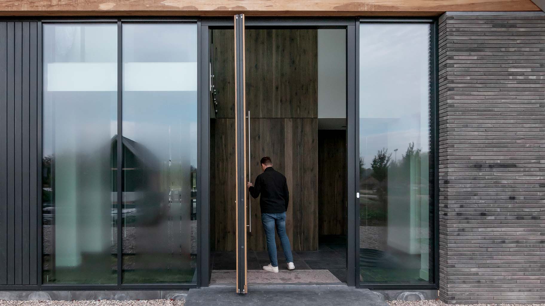 Moderne villa met hoge houten taatsdeur als opvallende voordeur