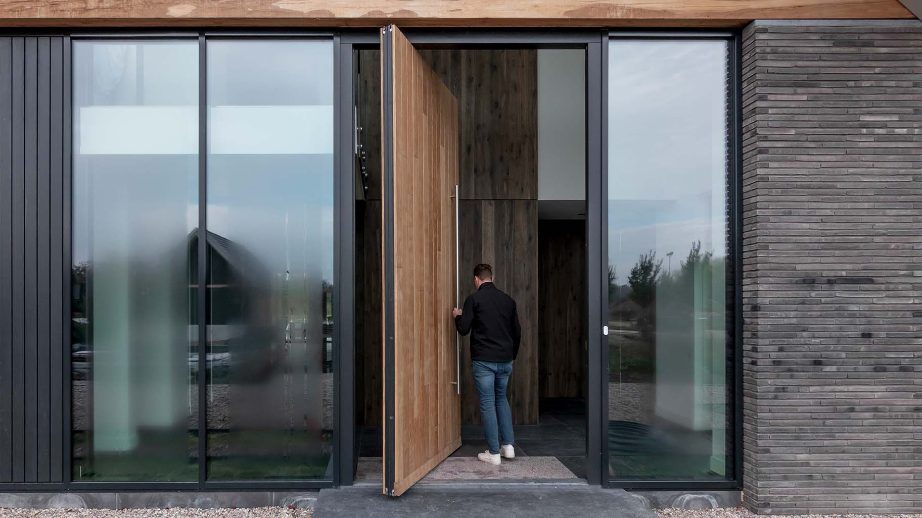 Moderne villa met hoge houten taatsdeur als opvallende voordeur