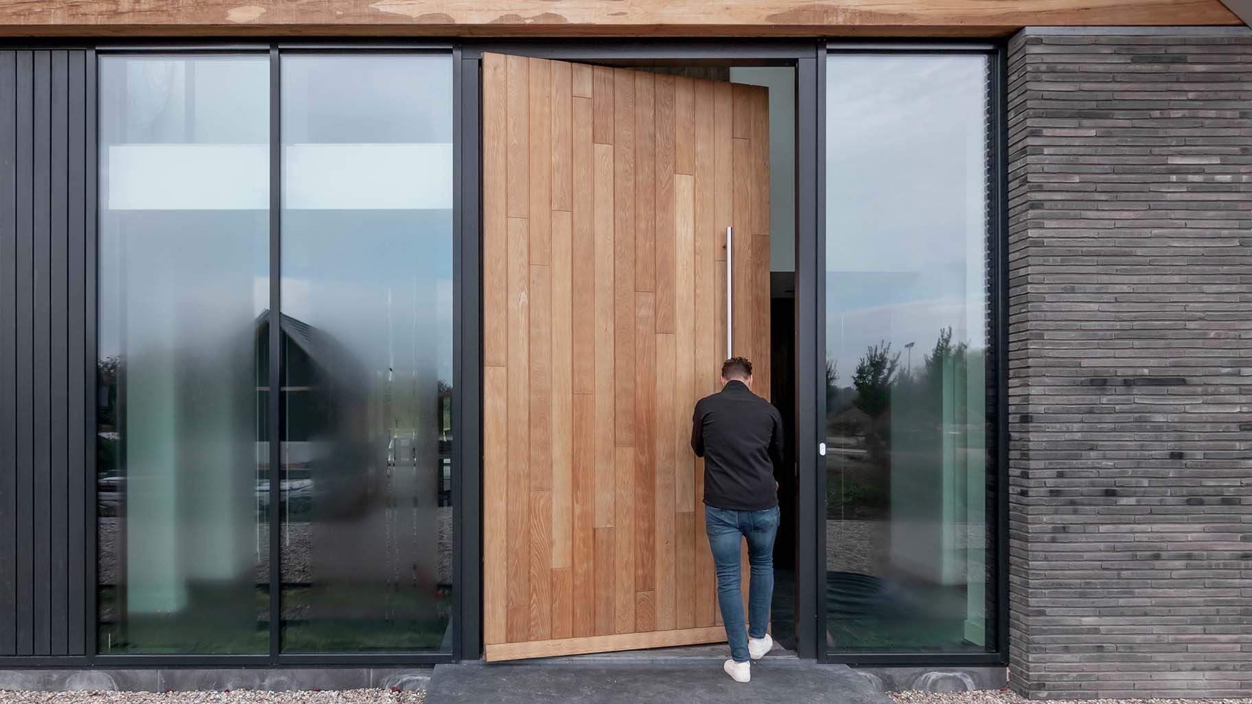 Moderne villa met hoge houten taatsdeur als opvallende voordeur