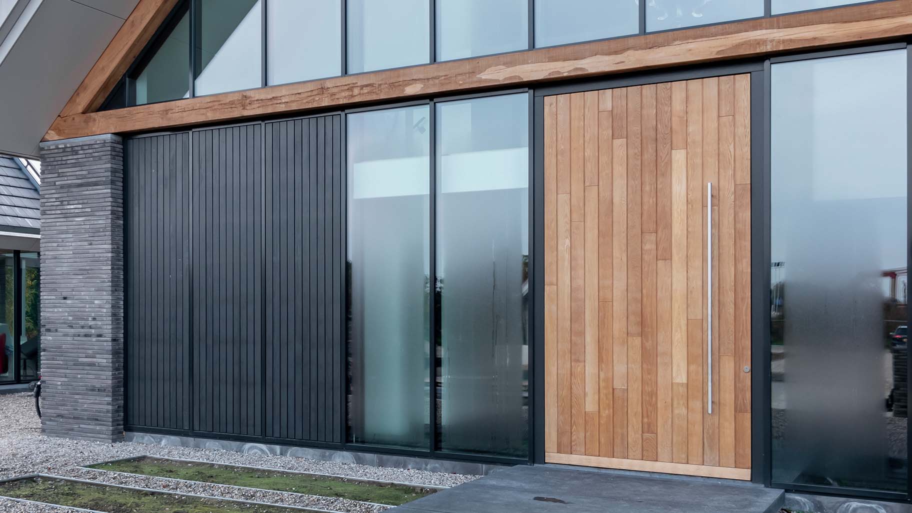 Houten taatsdeur verwerkt in de gevel van moderne villa