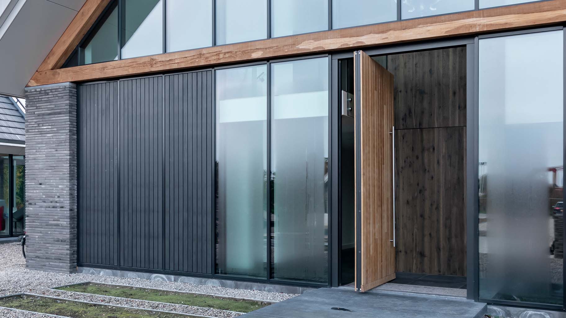 Houten taatsdeur verwerkt in de gevel van moderne villa