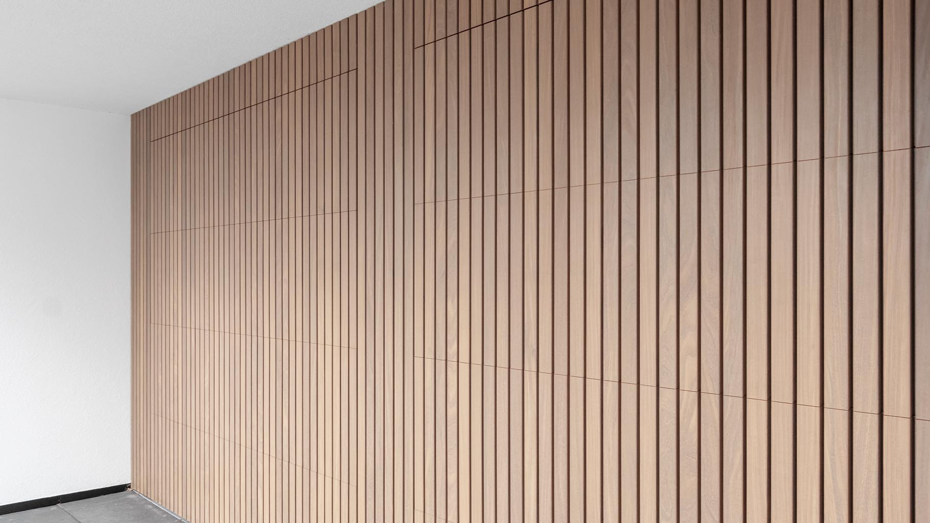 De Afrormosia houten garagedeuren en voordeur verstopt in de strakke gevel van de woning