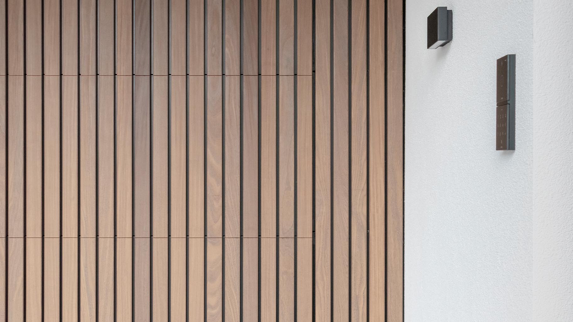 De Afrormosia houten garagedeuren en voordeur verstopt in de strakke gevel van de woning