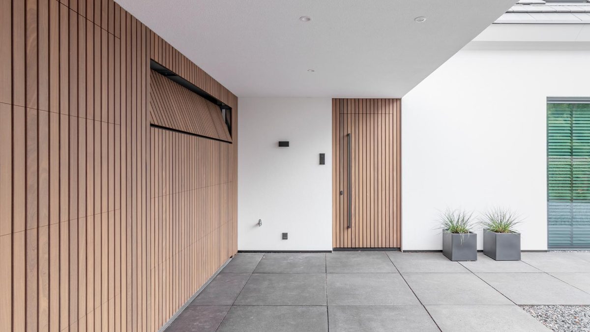 Moderne woning met Afrormosia houten garagedeuren en bijpassende voordeur die een luxe uitstraling geven aan het huis