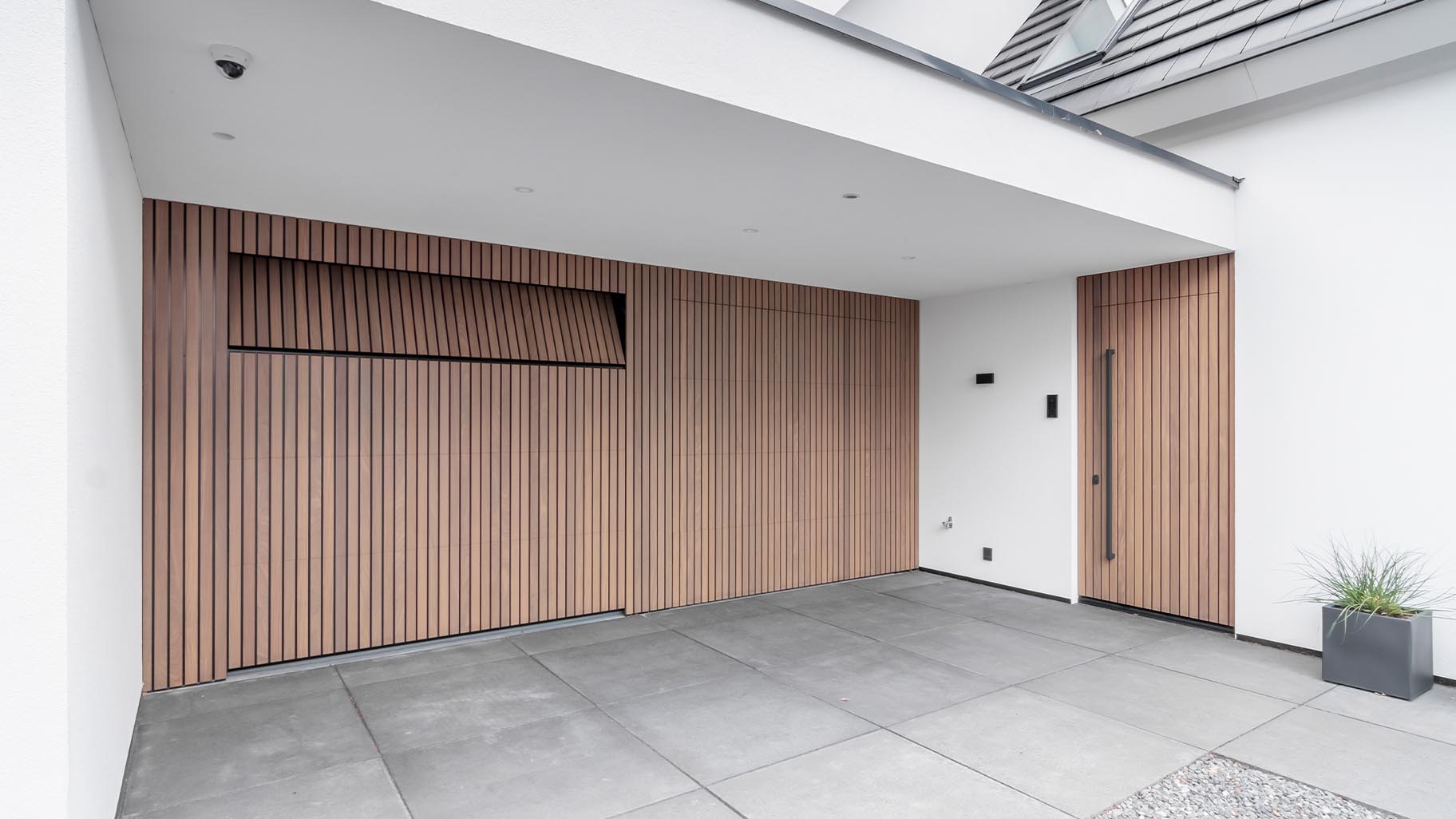 Moderne woning met Afrormosia houten garagedeuren en bijpassende voordeur die een luxe uitstraling geven aan het huis