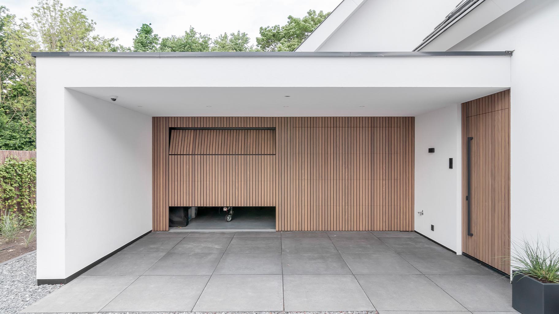 Moderne woning met Afrormosia houten garagedeuren en bijpassende voordeur die een luxe uitstraling geven aan het huis