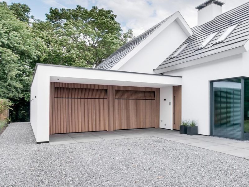 De Afrormosia houten garagedeuren en voordeur passen perfect in de strakke gevel van de woning
