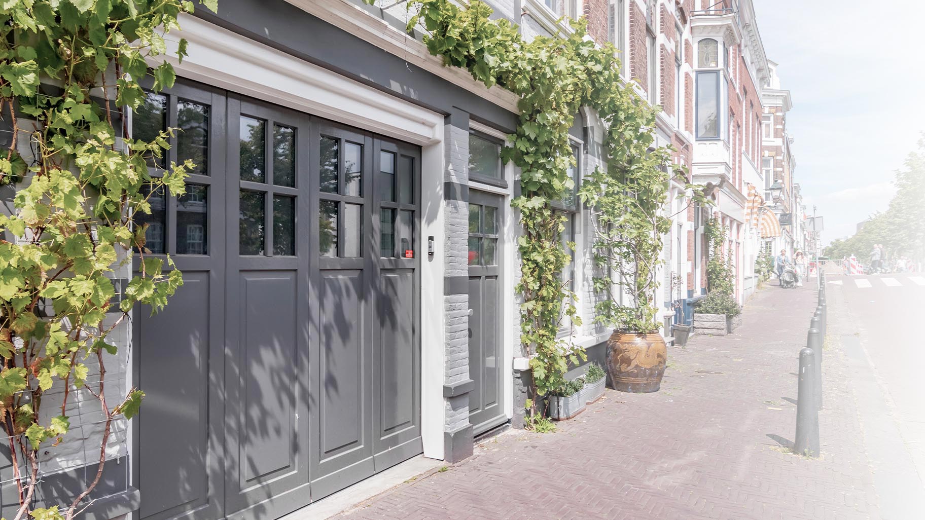 Een door Different Doors op maat gemaakte zijwaartse garagedeur, ontworpen om de klassieke esthetiek van deze monumentale woning