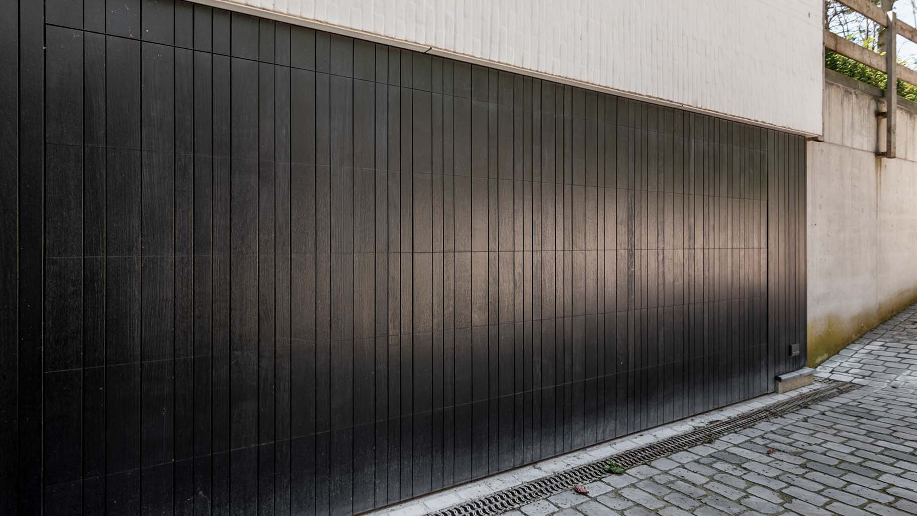 Donkere houten garagedeur gelijk in de gevel