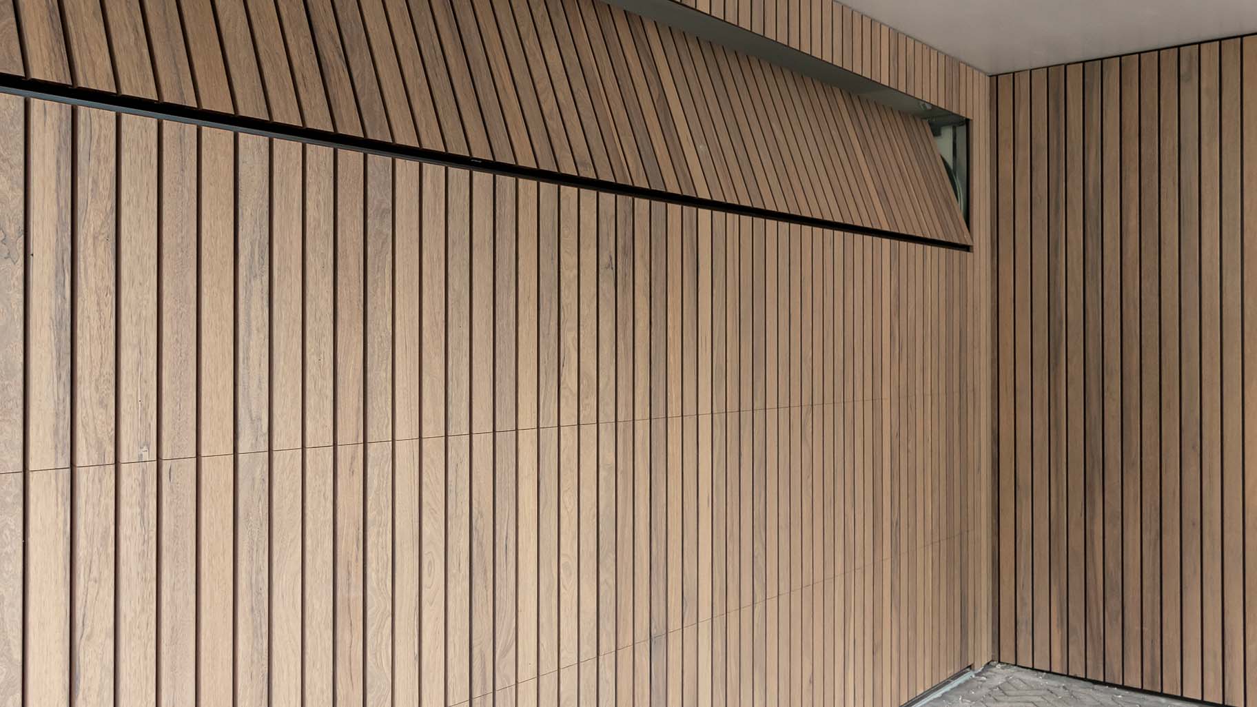 Moderne woning met Frake houten garagedeur en voordeur, passend bij de gevel