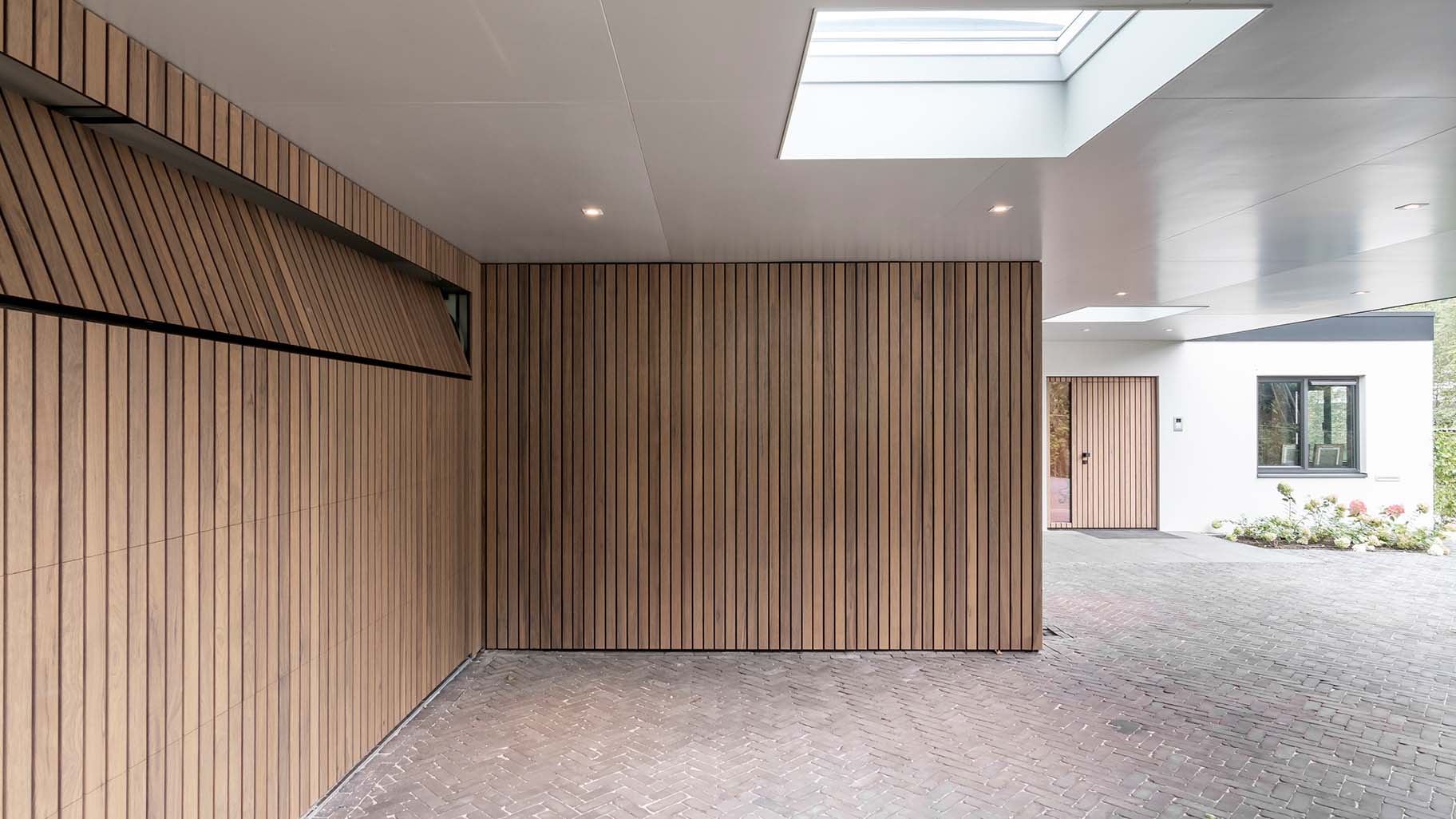 Frake houten garagedeur en voordeur, gelijk met de gevel