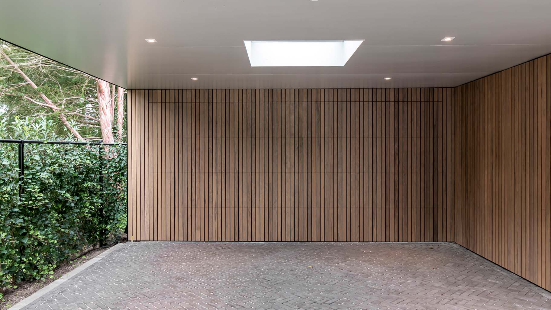 Frake houten garagedeur en voordeur, gelijk met de gevel