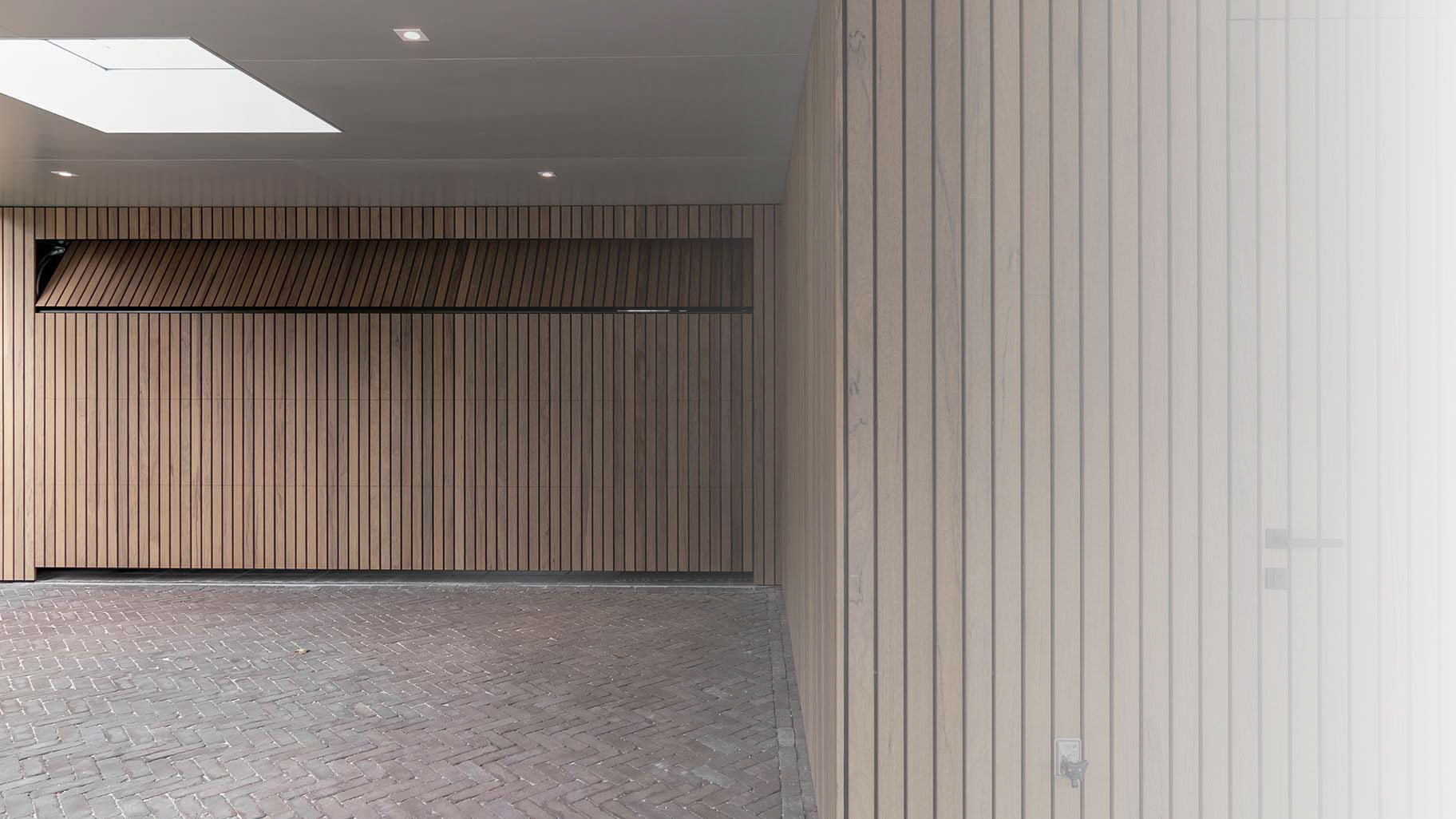 Different Doors garagedeur en voordeur van Frake hout, geïntegreerd in moderne gevel