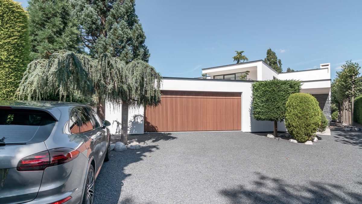 Houten garagedeur achter de dag bij moderne woning - Different Doors