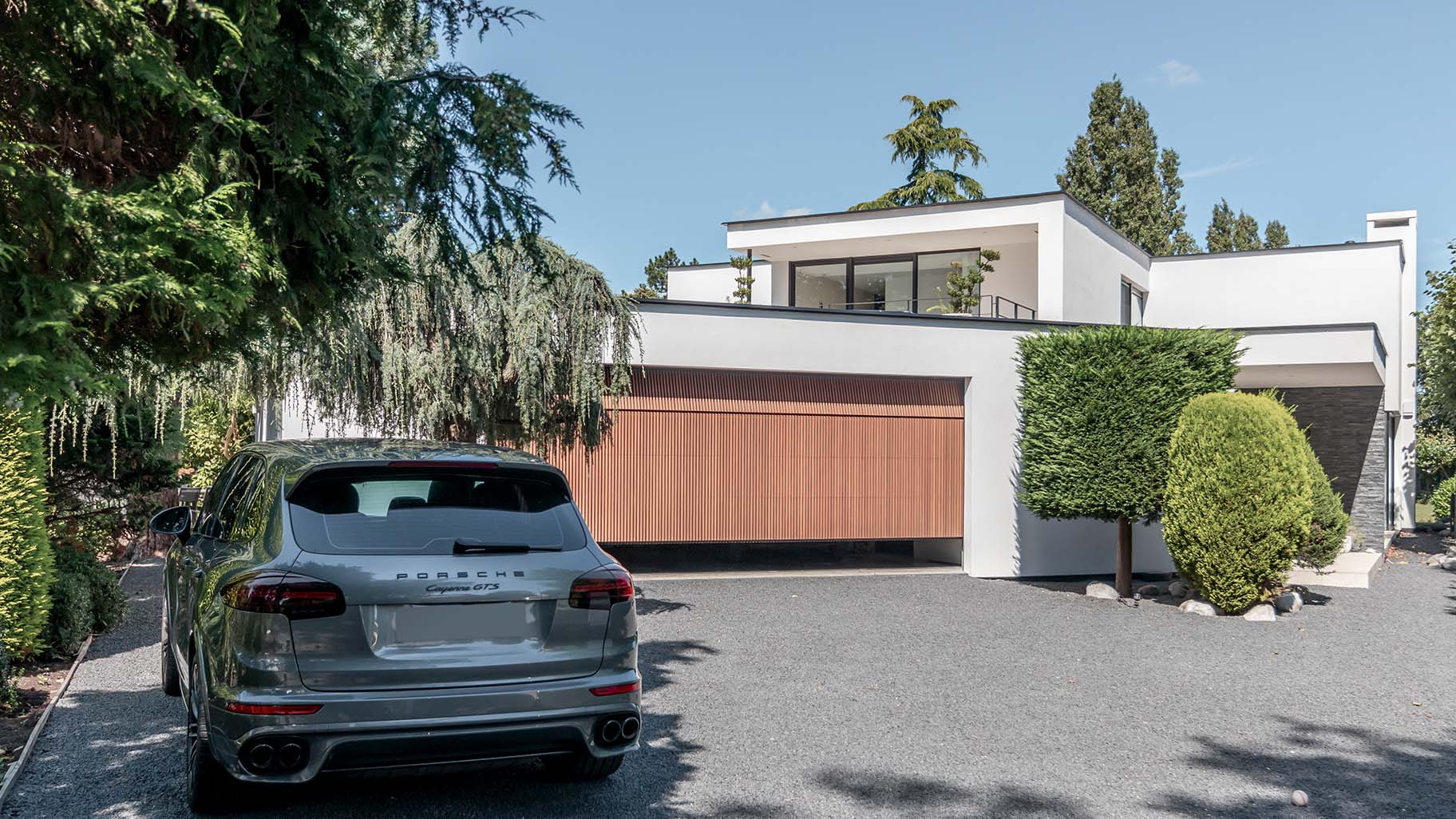 Houten garagedeur achter de dag bij moderne woning - Different Doors