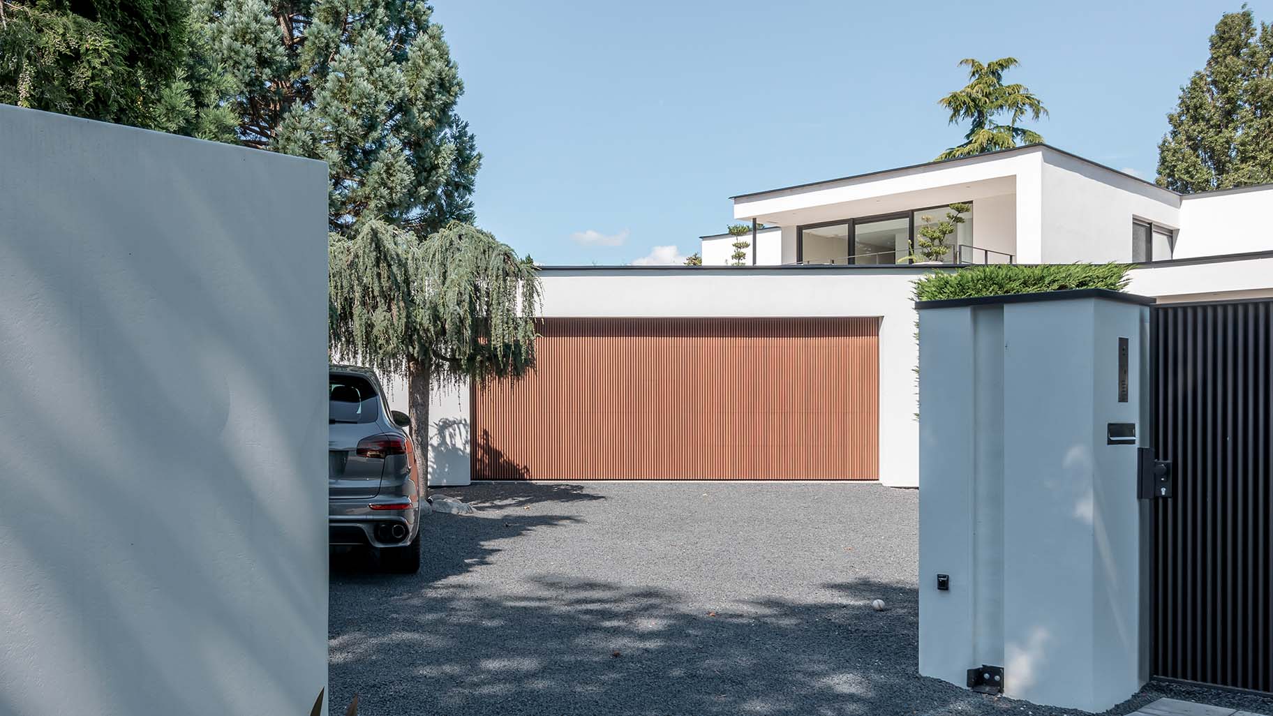 Houten garagedeur achter de dag bij moderne woning - Different Doors