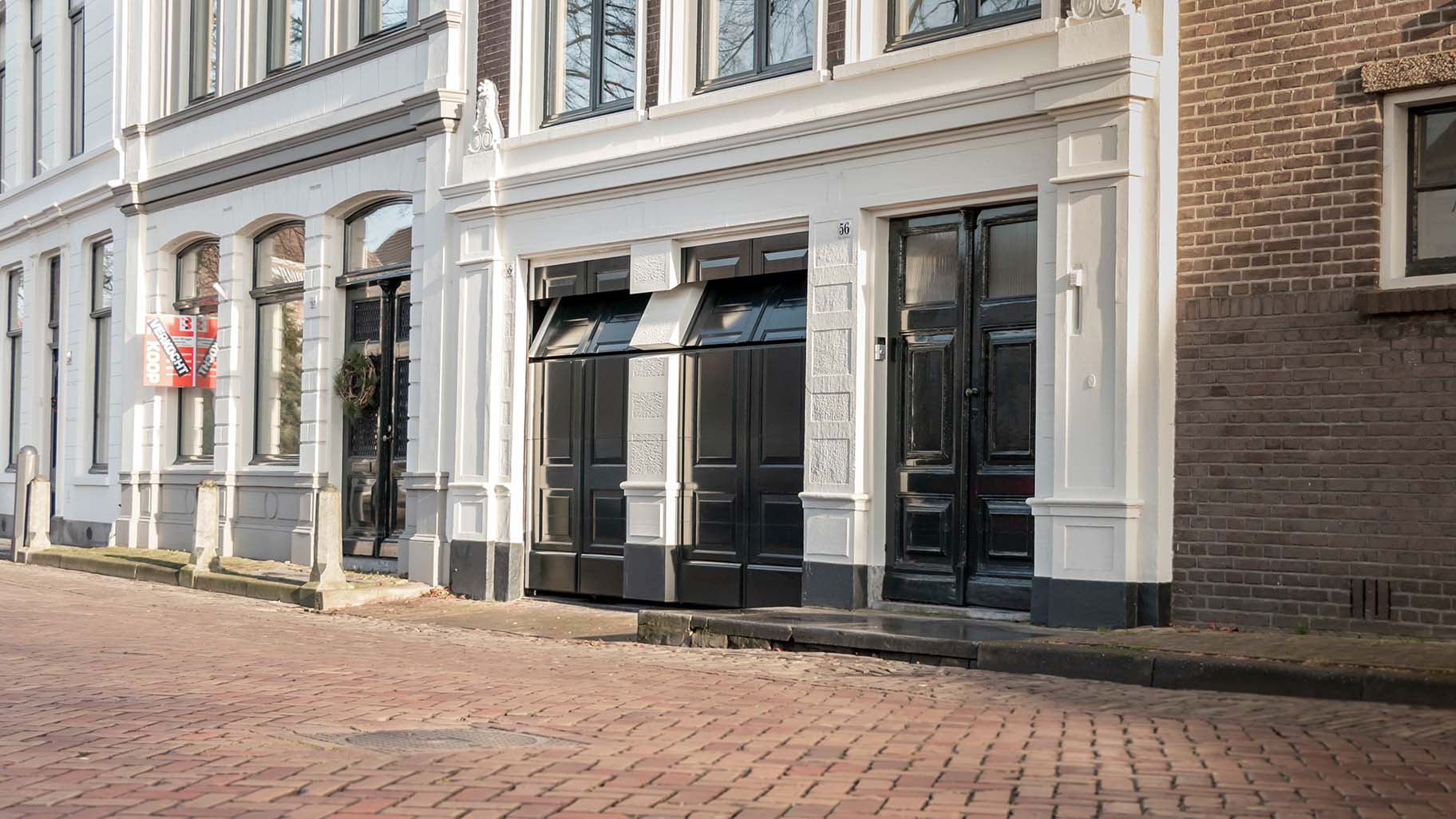 Onzichtbare houten garagedeur volledig geïntegreerd in de gevel van monumentaal pand in Gorinchem