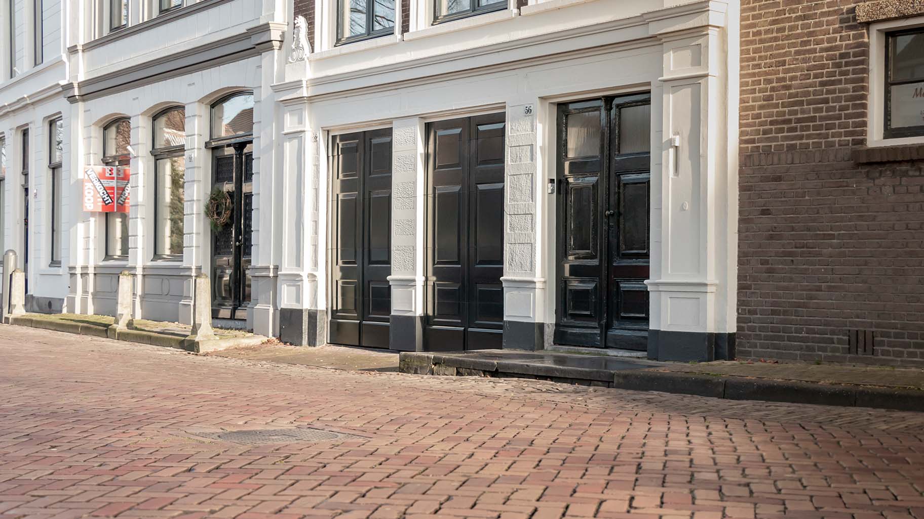 Onzichtbare houten garagedeur volledig geïntegreerd in de gevel van monumentaal pand in Gorinchem