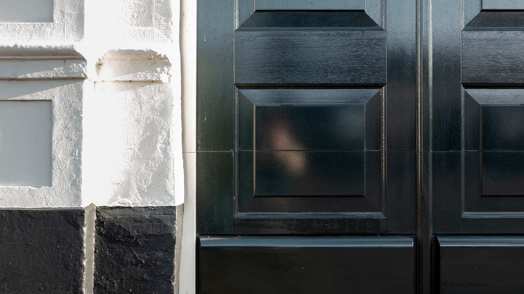 Detail van houten garagedeur met klassieke panelen en authentieke houtnerf in monumentaal pand