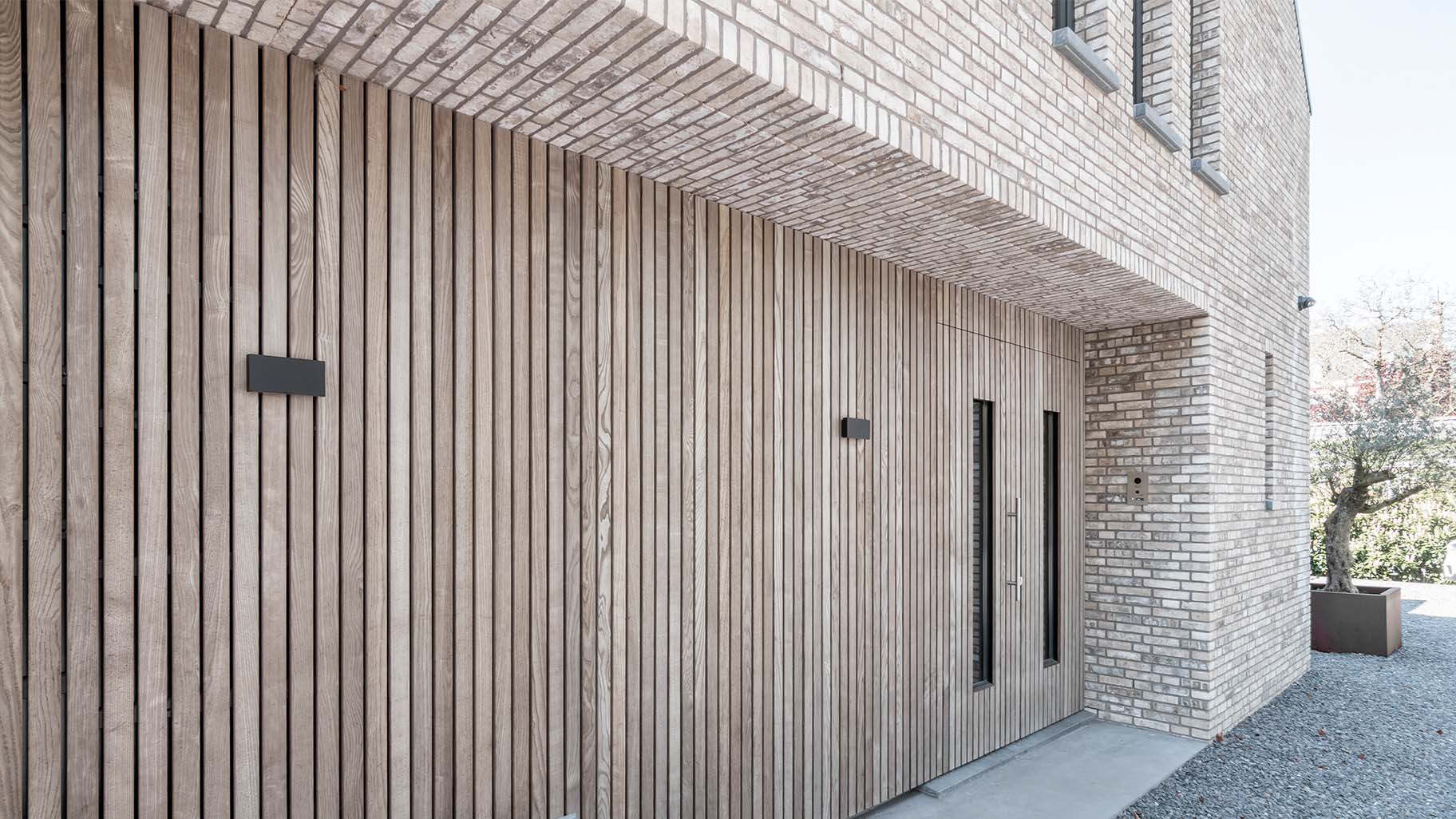 Onzichtbare houten garagedeur geïntegreerd in de gevel, gerealiseerd door Different Doors