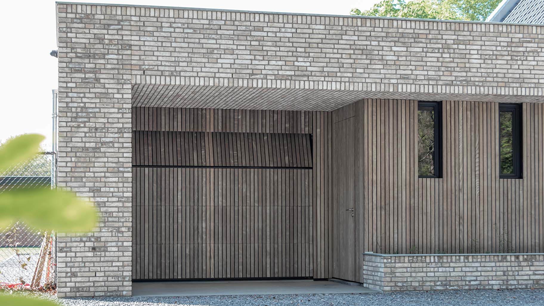 Onzichtbare houten garagedeur geïntegreerd in de gevel, gerealiseerd door Different Doors