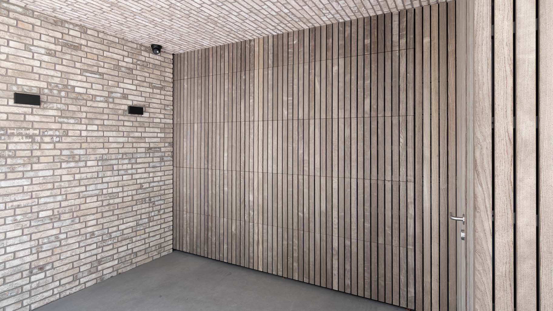 Onzichtbare houten garagedeur geïntegreerd in de gevel, gerealiseerd door Different Doors
