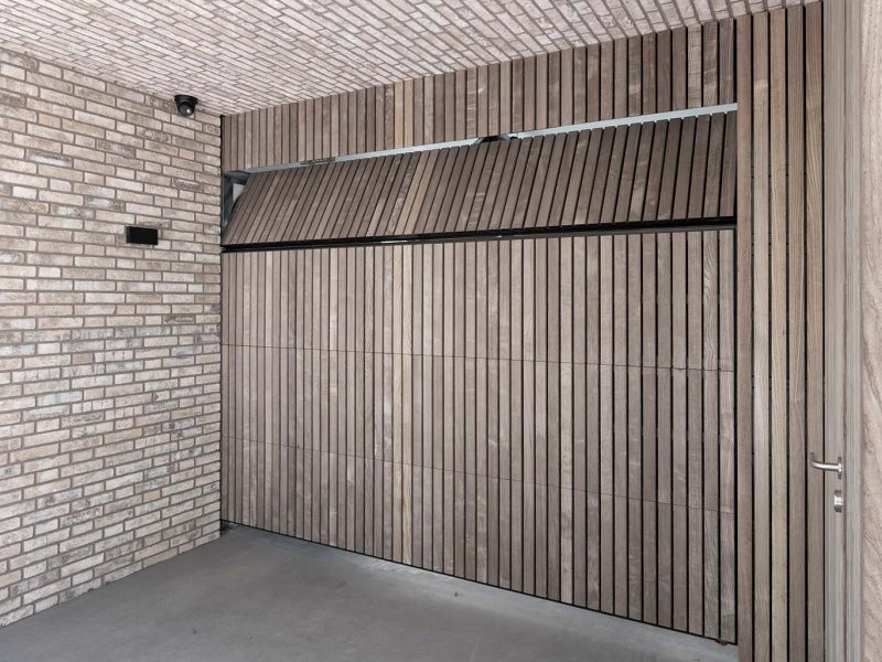 Onzichtbare houten garagedeur geïntegreerd in de gevel, gerealiseerd door Different Doors