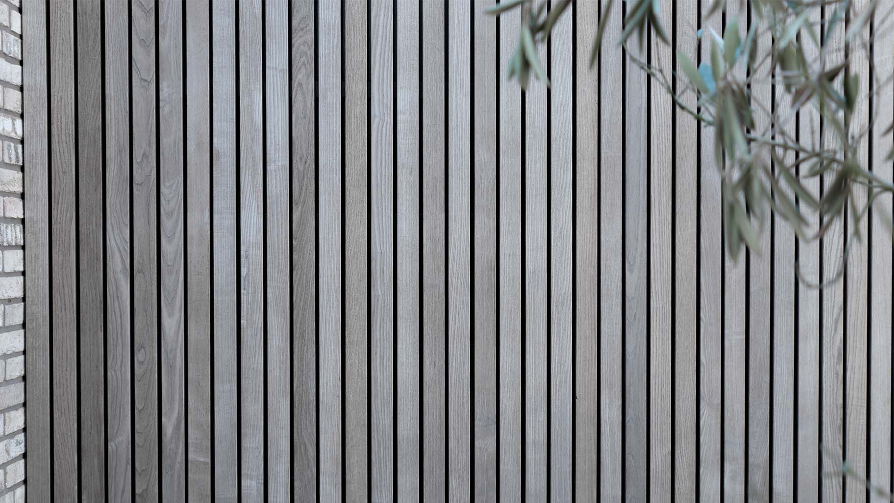 Detail van vergrijsd Essen hout in garagedeur en gevel