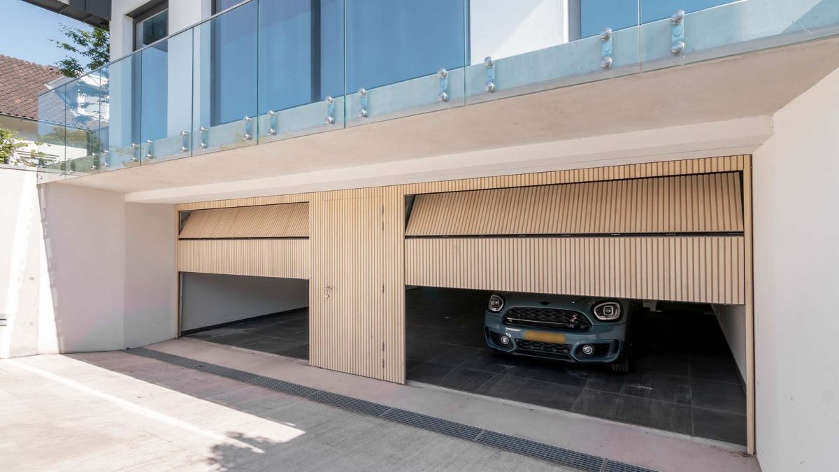 Garage met op maat gemaakte Accoya houten sectionaaldeuren en geïntegreerde loopdeu
