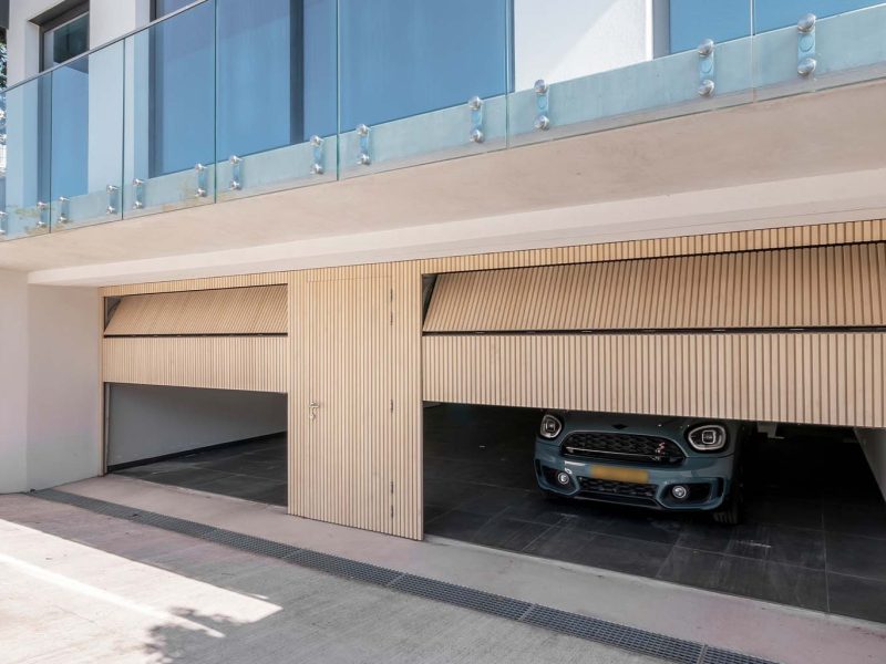 Garage met op maat gemaakte Accoya houten sectionaaldeuren en geïntegreerde loopdeu