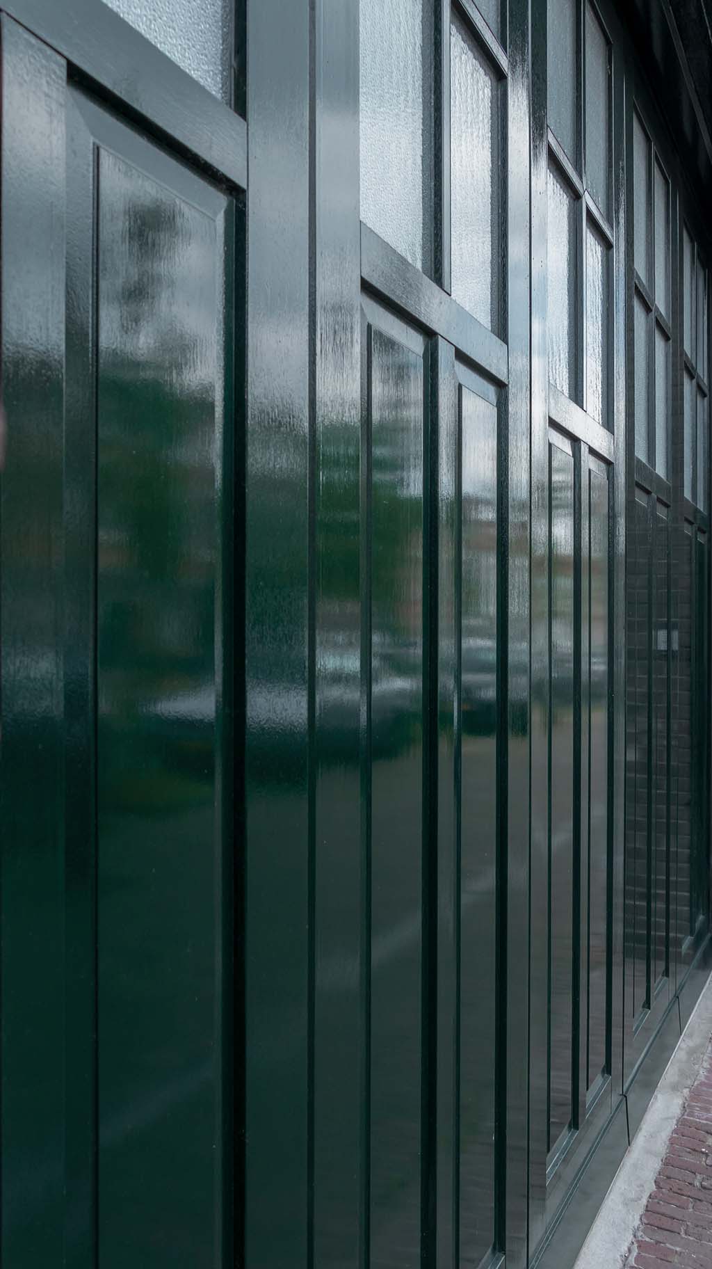 houten zijwaartse garagedeur met klassieke bossingpanelen en glas-in-loodramen