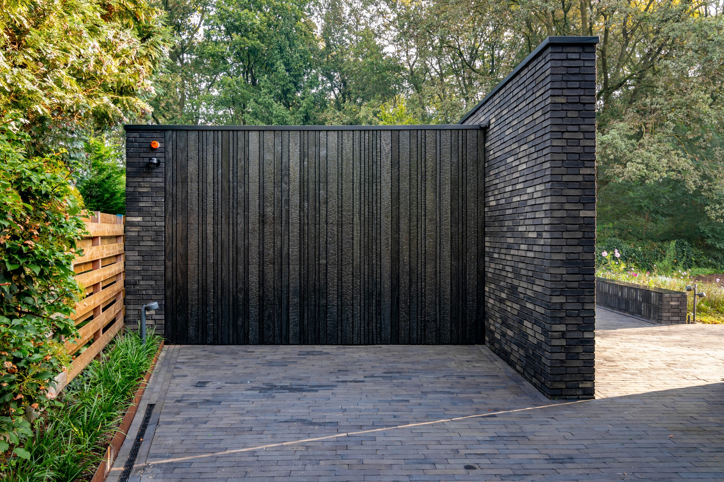 Different Doors Shou Sugi Ban garagedeur volledig verdwenen in moderne gevel