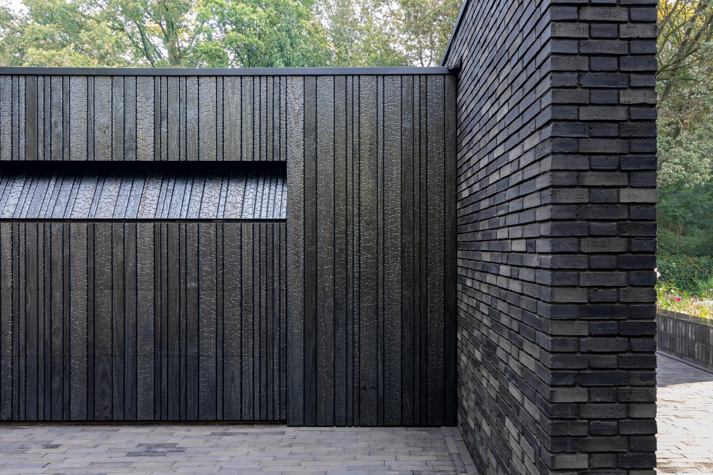 Shou Sugi Ban garagedeur verborgen in de gevel voor een strakke uitstraling