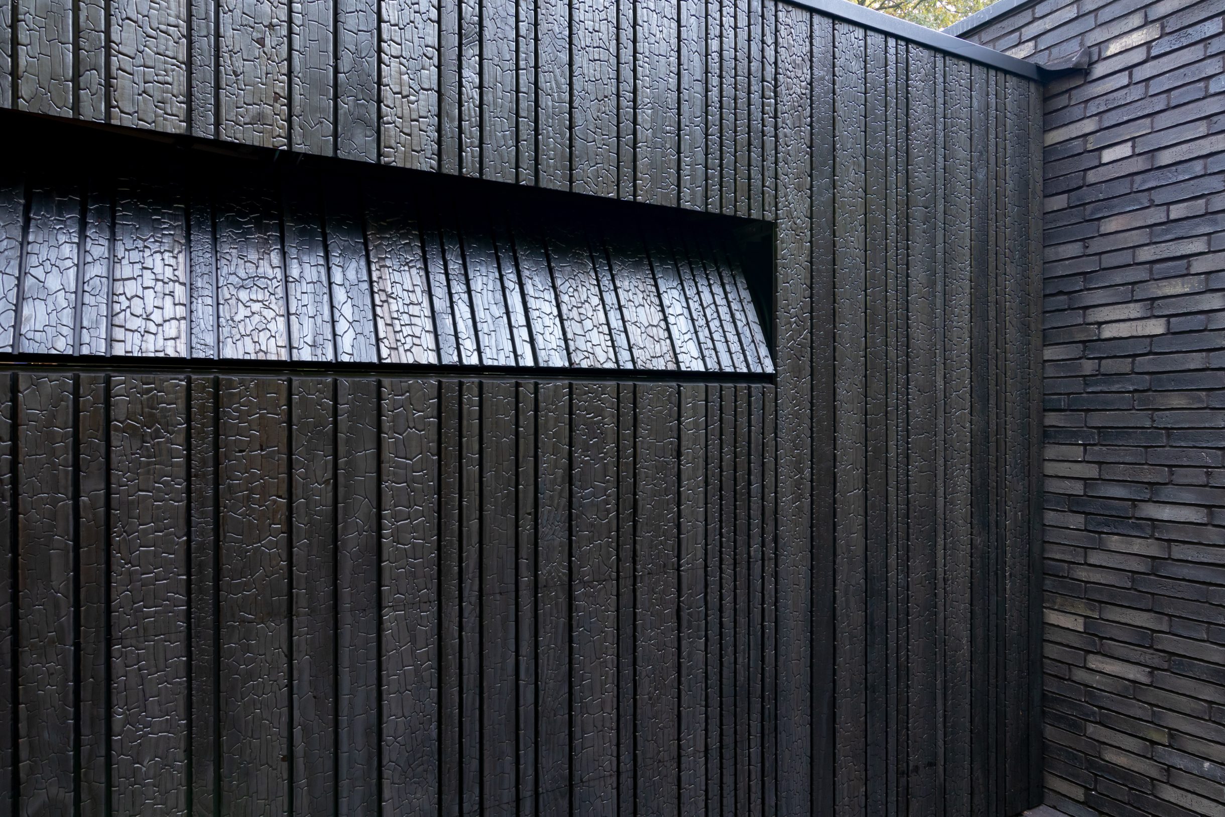 Shou Sugi Ban garagedeur verborgen in de gevel voor een strakke uitstraling