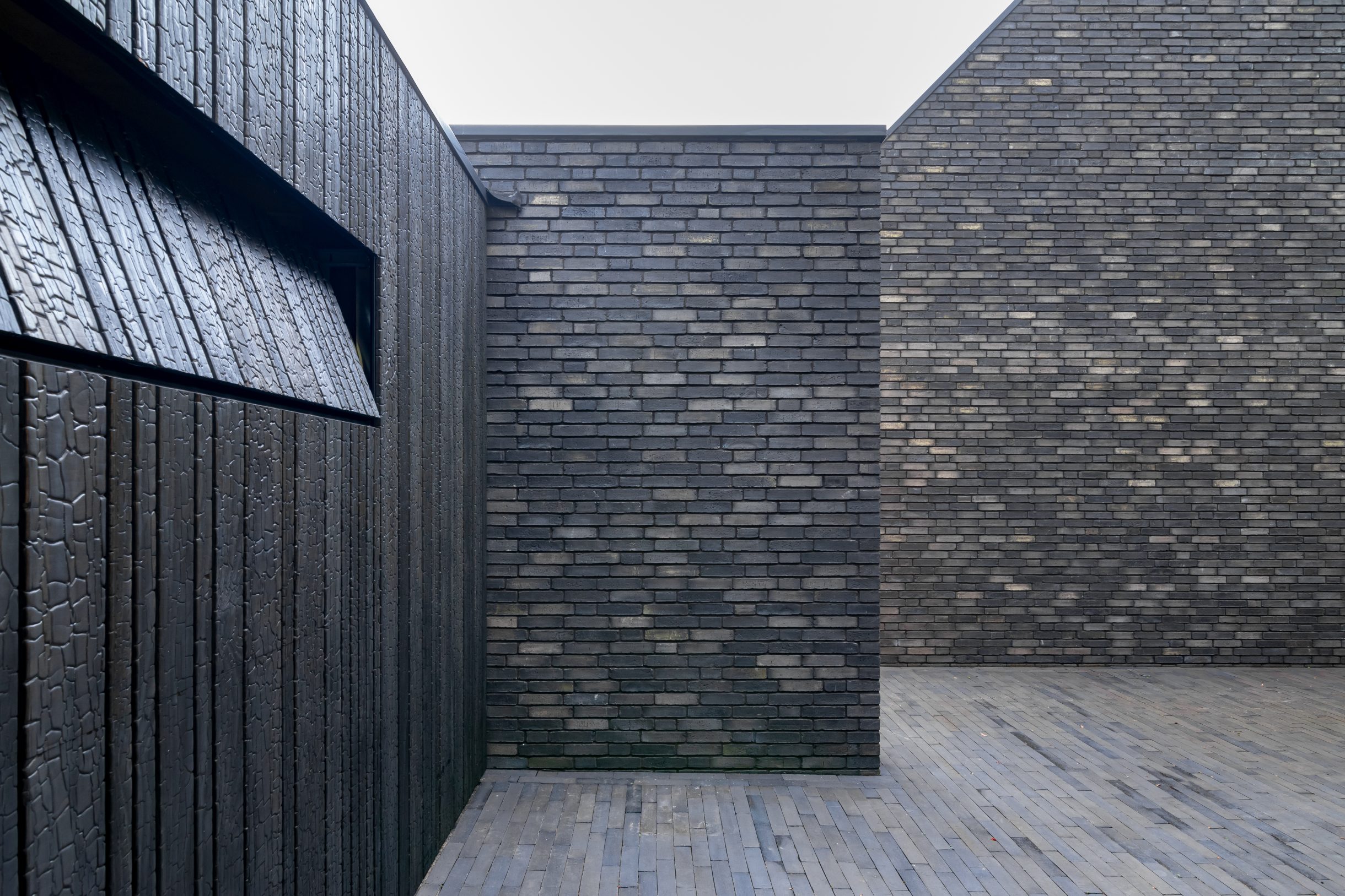 Moderne garage met Shou Sugi Ban garagedeur voor een minimalistische ontwerp