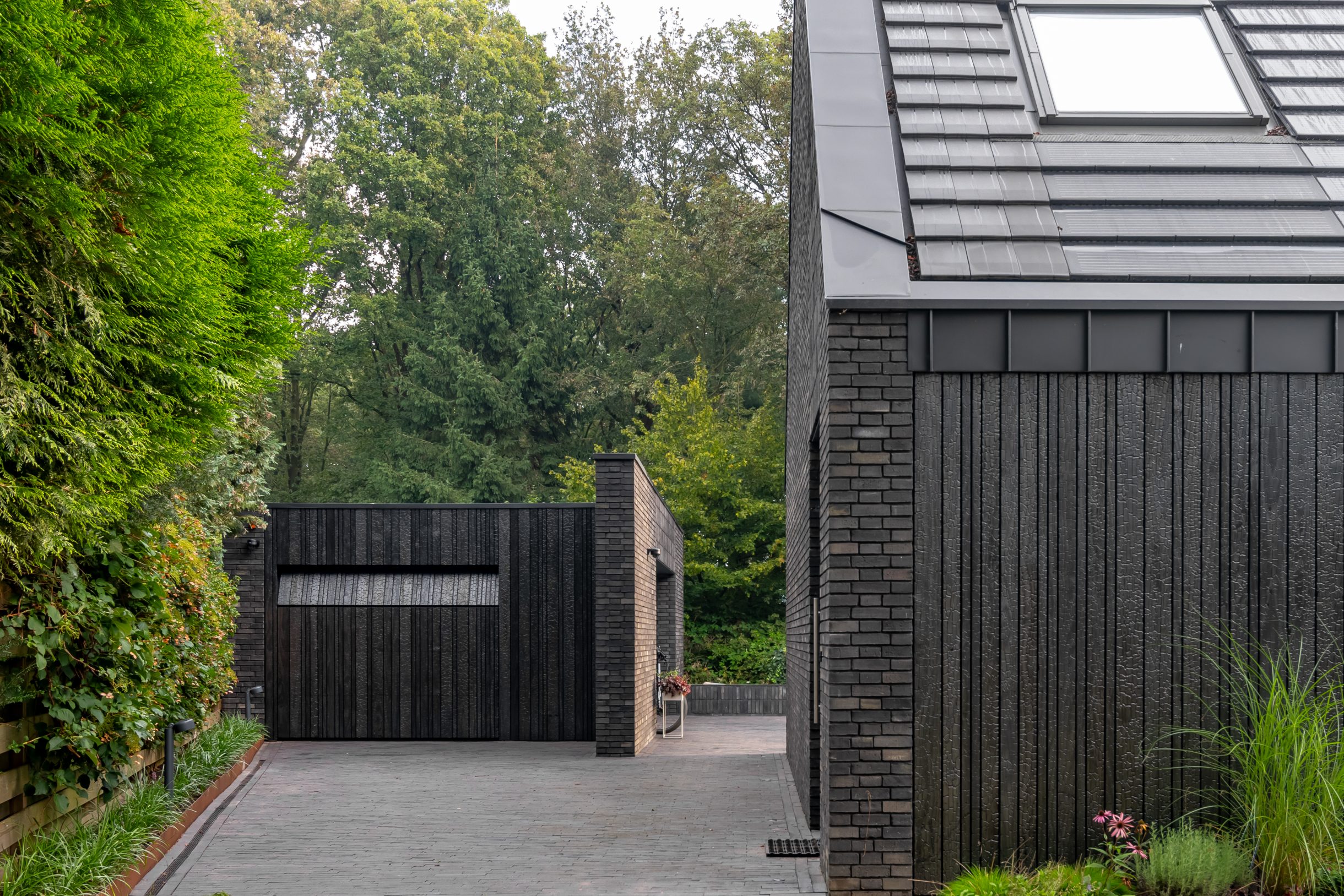 Moderne garage met Shou Sugi Ban garagedeur voor een minimalistische ontwerp