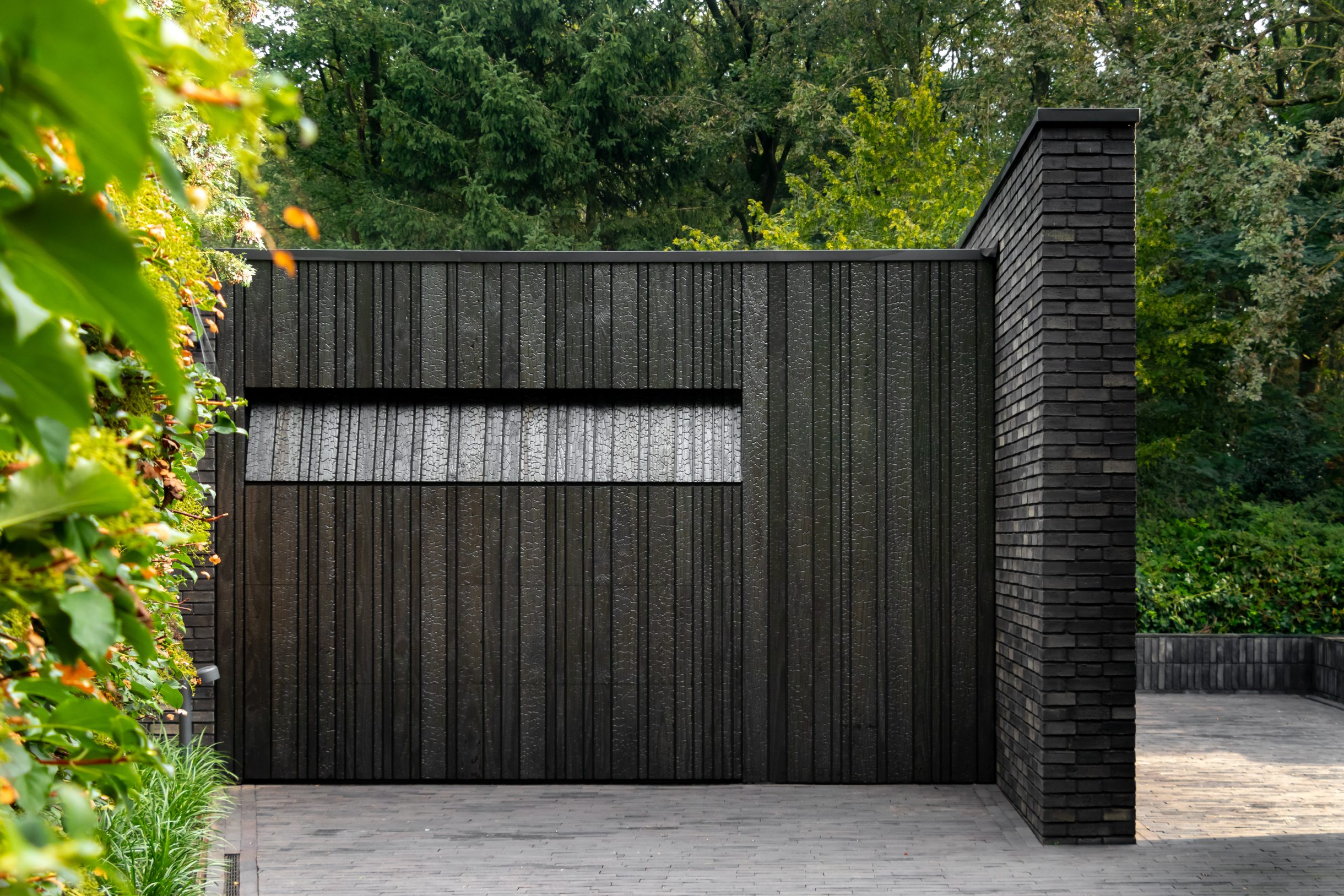Shou Sugi Ban garagedeur verborgen in de gevel voor een strakke uitstraling