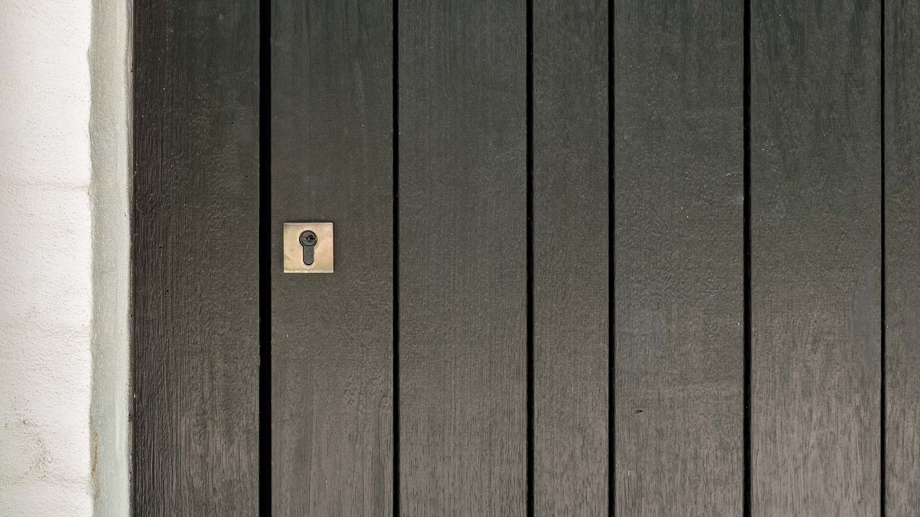 Pivoterende houten taatsdeur en garagedeur in dezelfde stijl different doors