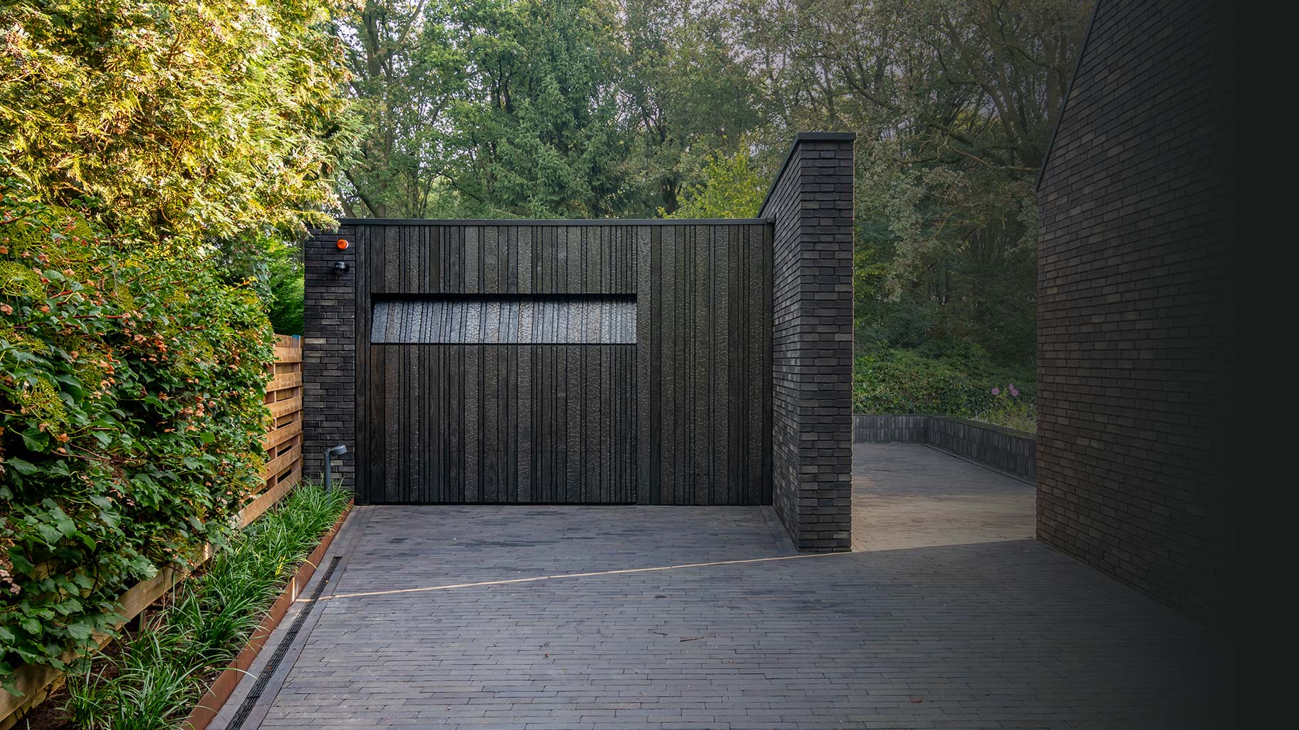 Shou Sugi Ban garagedeur verborgen in de gevel voor een strakke uitstraling