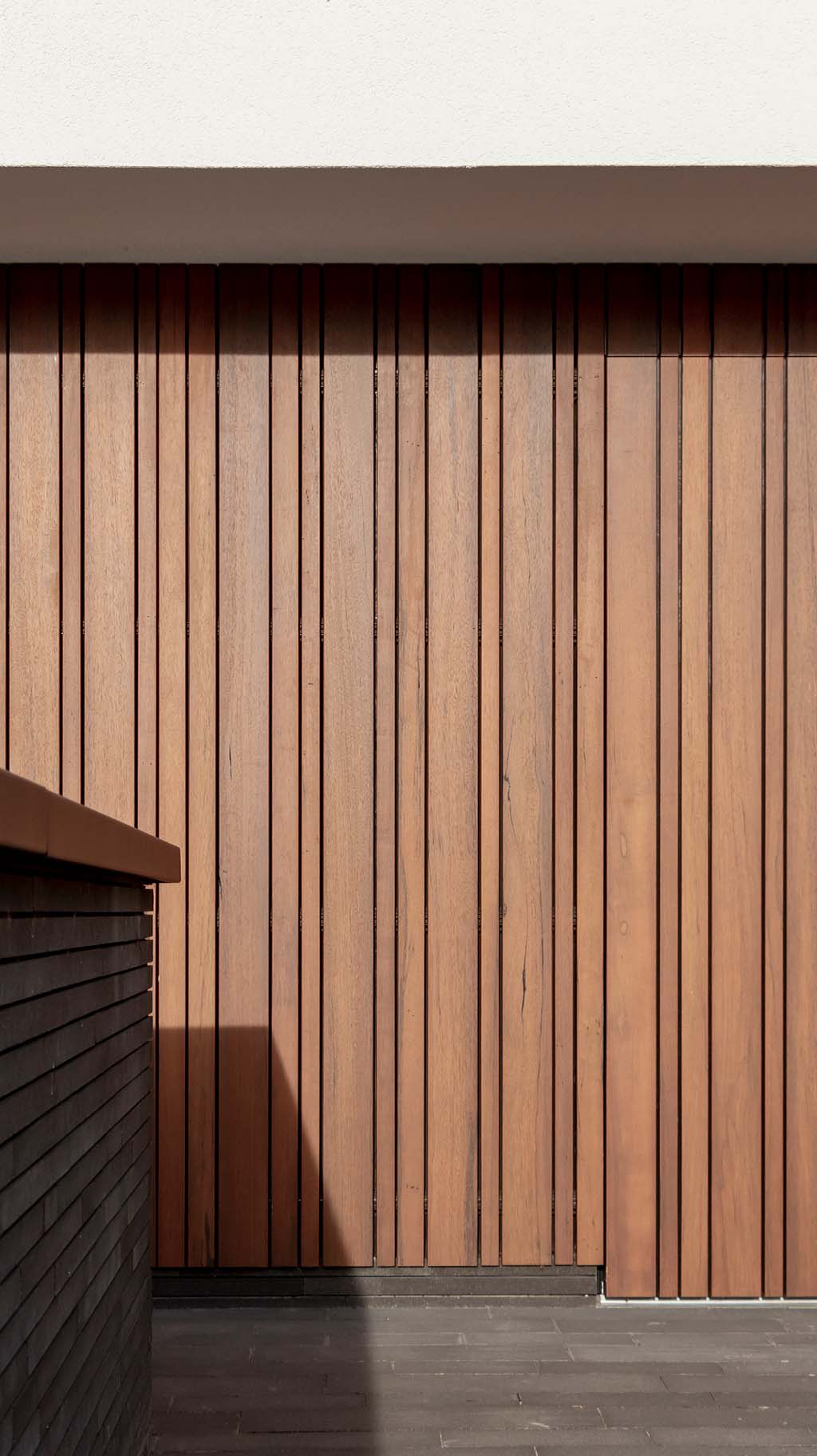 Detail van fraké houten garagedeur met zes perfect uitgelijnde secties en zichtbare houtnerf