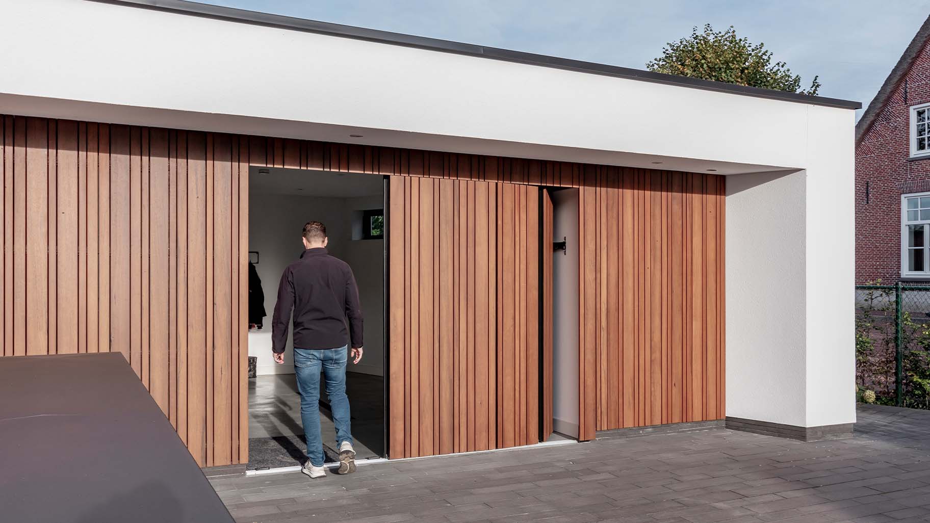 Different Doors zijwaartse garagedeur van fraké hout, naadloos geïntegreerd in moderne woning
