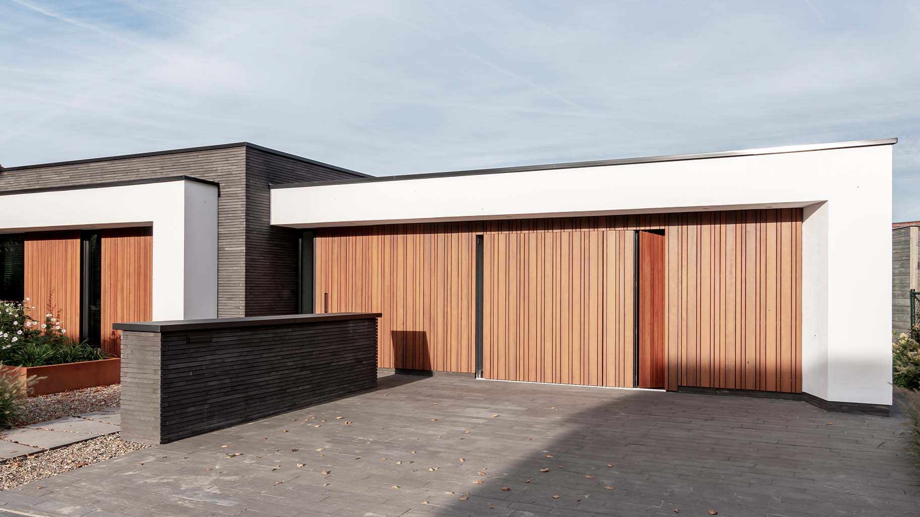 Different Doors zijwaartse garagedeur van fraké hout, naadloos geïntegreerd in moderne woning