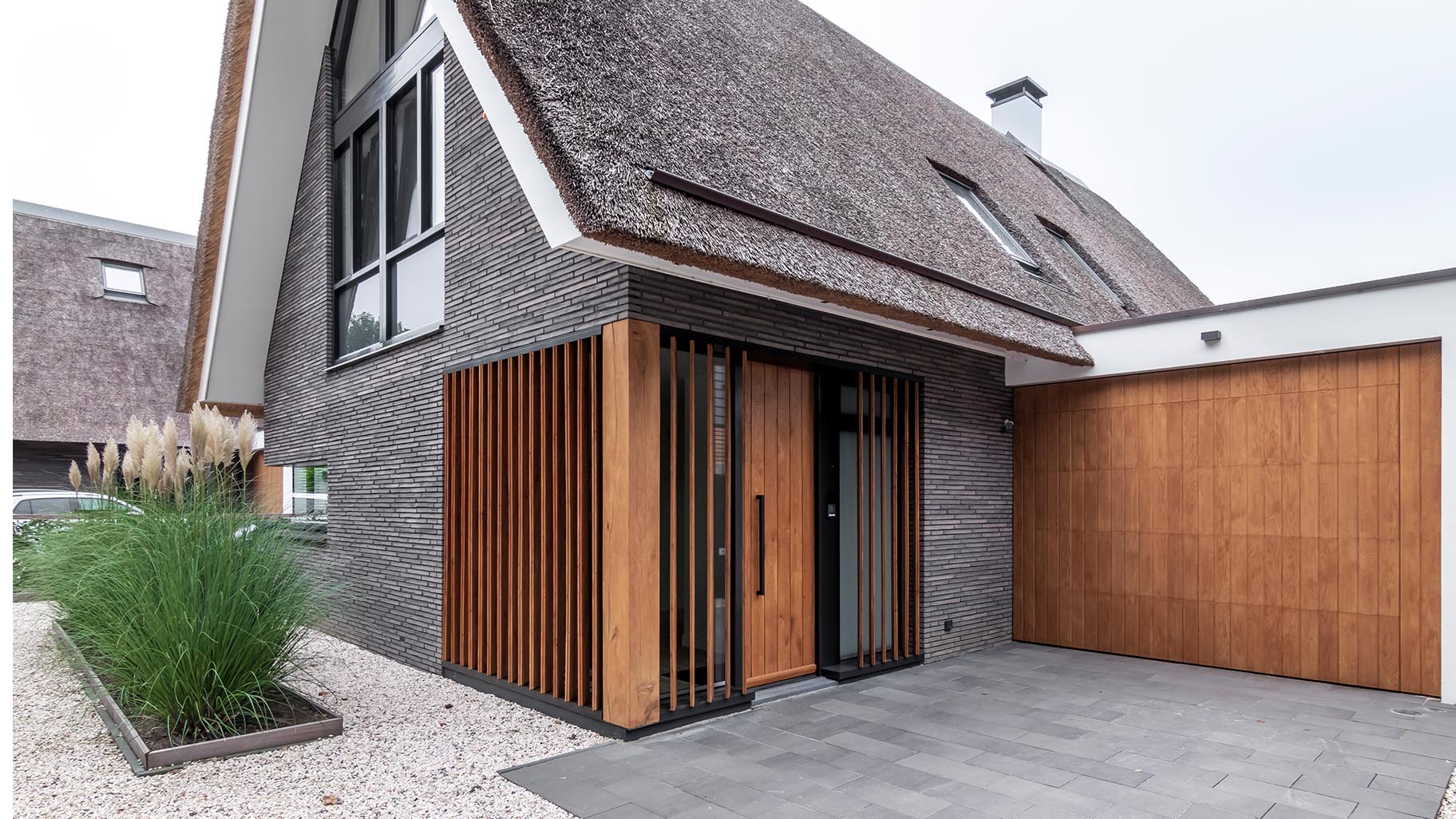 Moderne landelijke villa met een eikenhouten garagedeur, voordeur en gevelbekleding